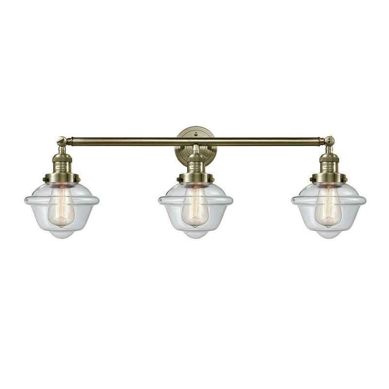 Oxford Bath Vanity Light shown in the Antique Brass finish with a Clear shade