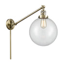 Beacon Swing Arm shown in the Antique Brass finish with a Clear shade