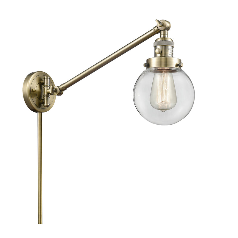 Beacon Swing Arm shown in the Antique Brass finish with a Clear shade