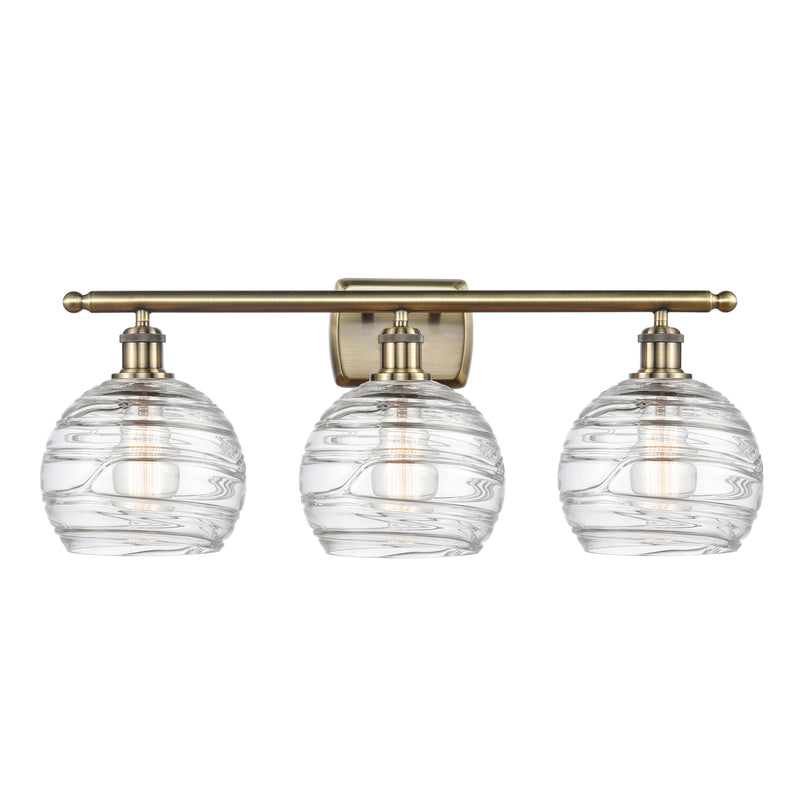 Deco Swirl Bath Vanity Light shown in the Antique Brass finish with a Clear shade